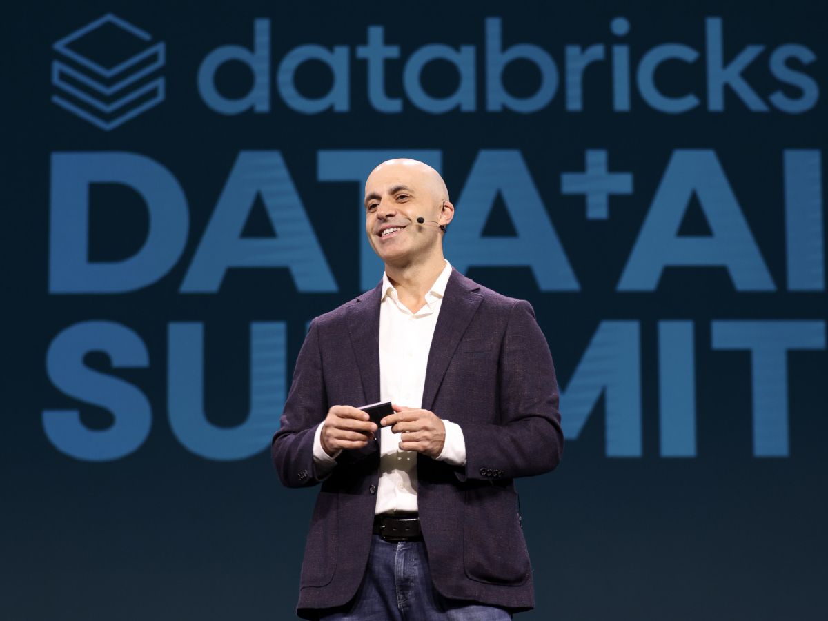 man dtands at dais with Data + AI summit in large font behind